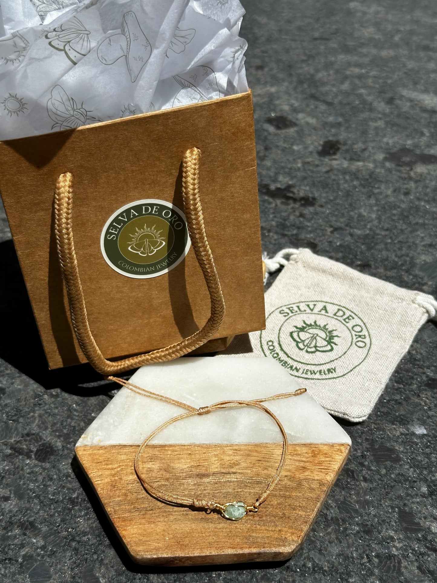 Raw Colombian emerald wrapped in gold wire and set on an adjustable gold cord with Selva de Oro branded gift bag and muslin pouch